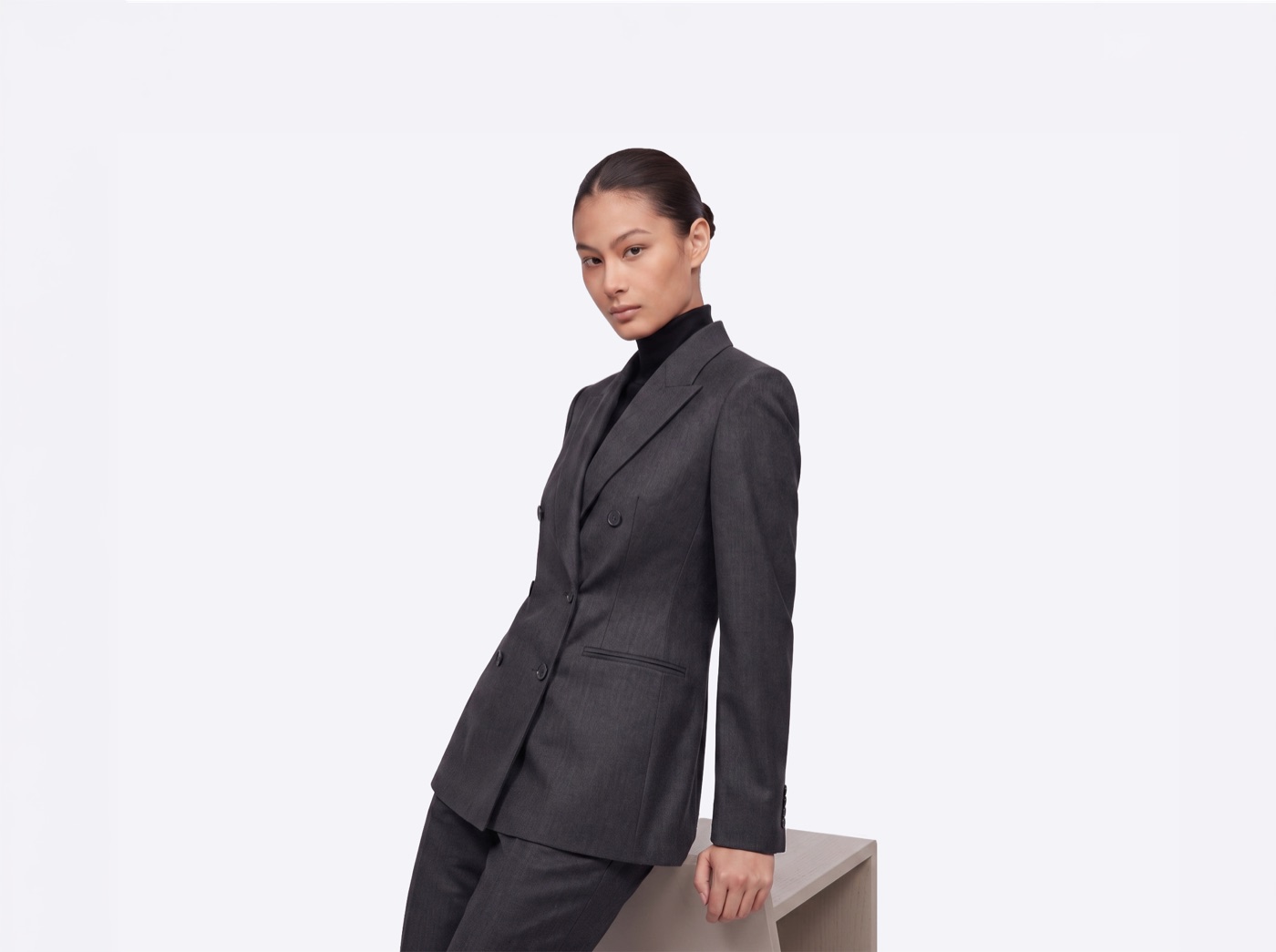 Model in a charcoal double-breasted suit leaning on a plinth